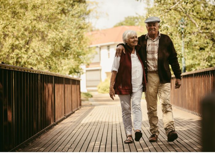 elderly couple walking with homes in background